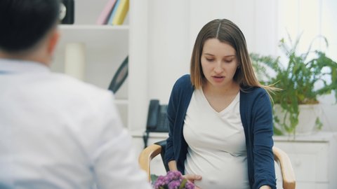 4k video of sad pregnant woman talking with a doctor.