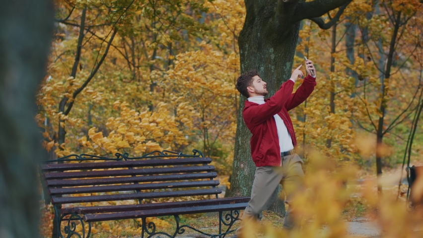 Young attractive excited guy starting to dance, watching internet video tutorial and repeating choreography moves. Dancing man. Outdoor park.