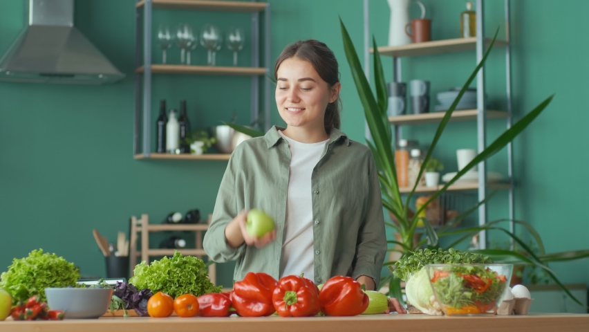Happy Young Woman Enjoying The Process of Cooking, Having Fun Playing With an Apple at the Kitchen Table with Organic Products. Diet, Proper Nutrition, Raw Food Diet. Nutrition and Dietetics. Royalty-Free Stock Footage #1086519206