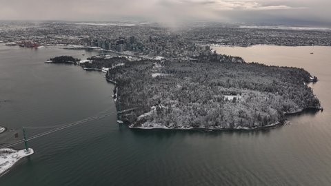 Vancouver, British Columbia, Canada - Aerial view of Stanley Park and lions gate bridge on a Snowy Winter day in 4K