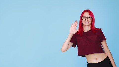 Say hello. Bye gesture. Advertising background. Boomerang motion. Cheerful smiling greeting woman waving hand isolated on blue empty space background GIF loop.
