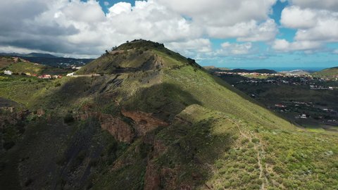 Ancient Pico de Bandama volcano in Gran Canaria, located on the edge of a volcanic crater against the backdrop of lush green valleys and small villages of Canary islands. Stunning aerial view.