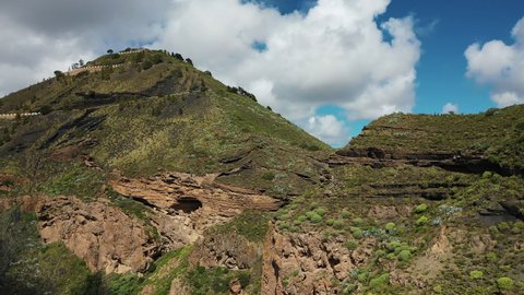 Spectacular rock formations on the edge of a volcano crater in Gran Canaria of Canary islands against the backdrop of lush green valleys.