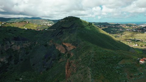 Birds eye view of ancient Pico de Bandama volcano in Gran Canaria, located on the edge of a volcanic crater against the backdrop of lush green valleys and small villages of Canary islands.