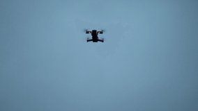 Closeup view of flying drone at overcast sky with grey clouds.