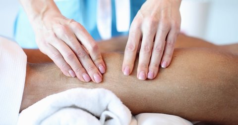 Masseuse massages shins to young man closeup