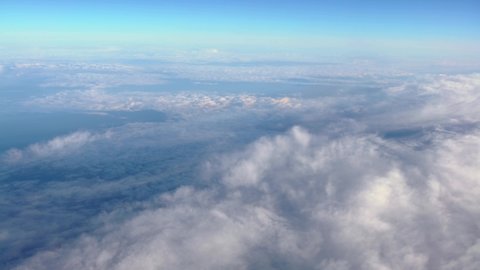 Wonderful view of cloudscape with clear blue sky from above. Beautiful panorama above white clouds as seen through window of an aircraft. A view from airplane.