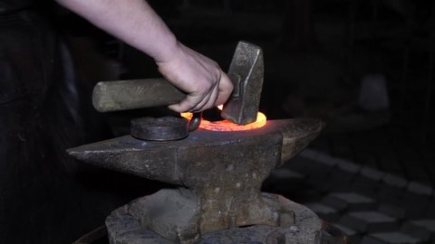 The blacksmith professionally makes a horseshoe for a horse from hot metal. The profession of a blacksmith. Craft.