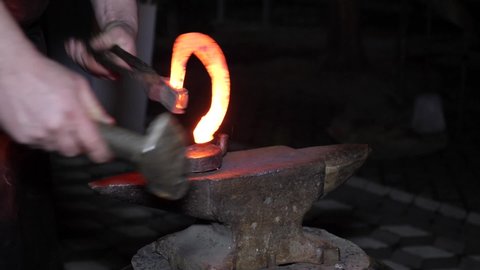 The blacksmith professionally makes a horseshoe for a horse from hot metal. The profession of a blacksmith. Craft.