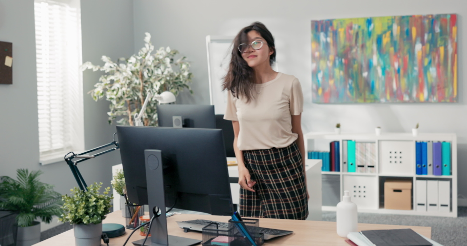 A beautiful woman dances in an office, a company, a corporation between the desks of co-workers, she is happy, smiling joyful, she finishes her job early, gets a promotion, changes position