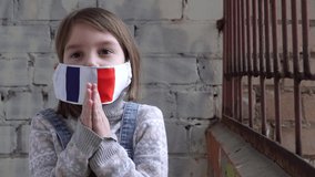 Little girl child wearing a protective medical mask with a french flag. Virus and disease concept, stay home. Thank you, praying hands hand gesture. Child saying "thank you" praying hands. - Powered by Shutterstock - Get 15% off with code: PIKWIZARD15