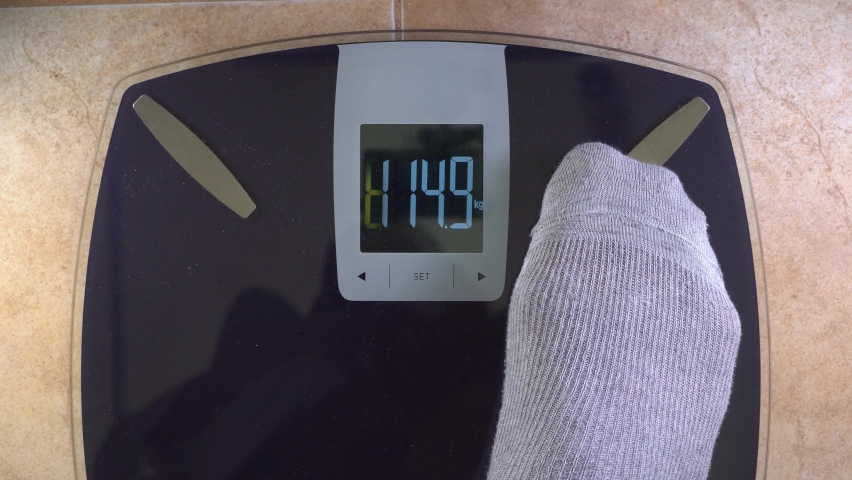 A man in gray cotton socks steps on the scales. The concept of the need to reduce weight. Obesity danger. Point of view. | Shutterstock HD Video #1086552077