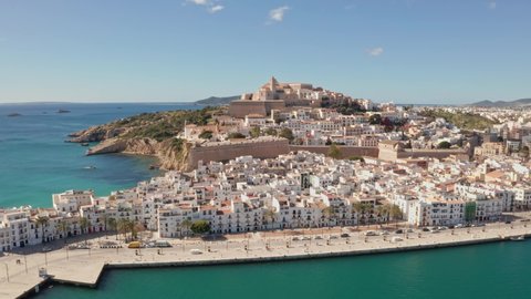 Aerial view of Ibiza city, the Old Town and the city walls of Eivissa with an ocean foreground, filmed by drone, on a sunny and clear day.