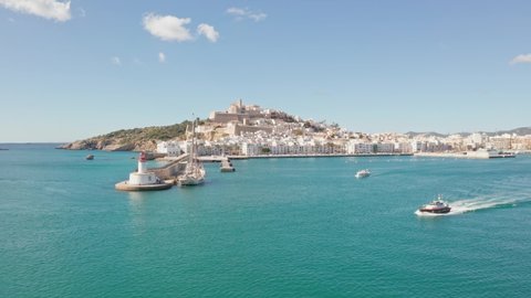 Ibiza, Spain - Boat leaving port of Ibiza City Eivissa. Filmed by drone aerial. Ibiza City in background, ocean in foreground, bird flying trough