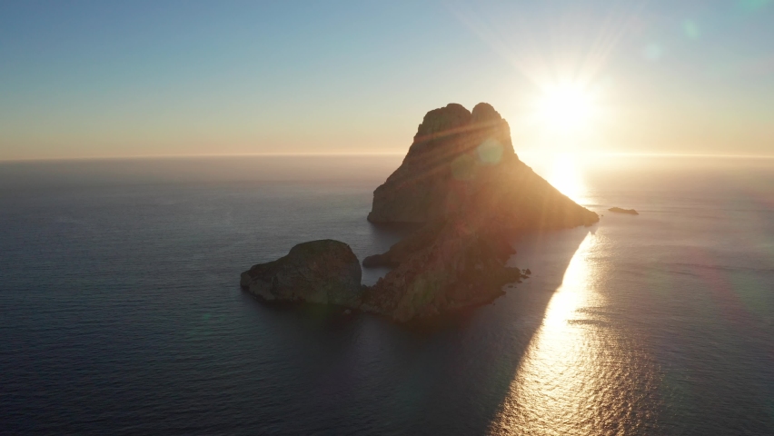 Aerial view of sun setting behind Es Vedra Ibiza during sunset. Showing ocean and clear skies. Royalty-Free Stock Footage #1086553808