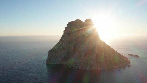 Aerial view of sunset behind Es Vedra Ibiza with sunrays. Showing ocean and clear skies. Panning right
