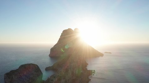 Aerial view of sunset behind Es Vedra Ibiza with sunstar. Showing ocean and clear skies. Moving towards Es Vedra and panning down.