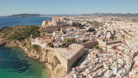 Aerial view of Ibiza city, the Old Town and the city walls of Eivissa with an ocean foreground, filmed by drone, Dolly outement, on a sunny and clear day.