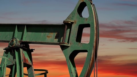 Petroleum Industry Pump Jack Extracting Crude Oil from A Oil Well At Sunset. Fossil Fuel Energy. Oil Industry Equipment. Beautiful Orange Sky With Moving Clouds Above Working Oil Rig.