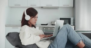 a girl lying on the couch in headphones looks at the laptop screen and makes a purchase decision