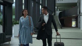 Young businesspeople talking and walking in airport lobby while waiting for flight spbd. American African businessman talks to businesswoman and looks with smile, gestures with hands and moves - Powered by Shutterstock - Get 15% off with code: PIKWIZARD15
