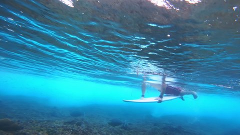 Amateur beginner surfer learns duck dive with surf board in the crystal clear ocean wave