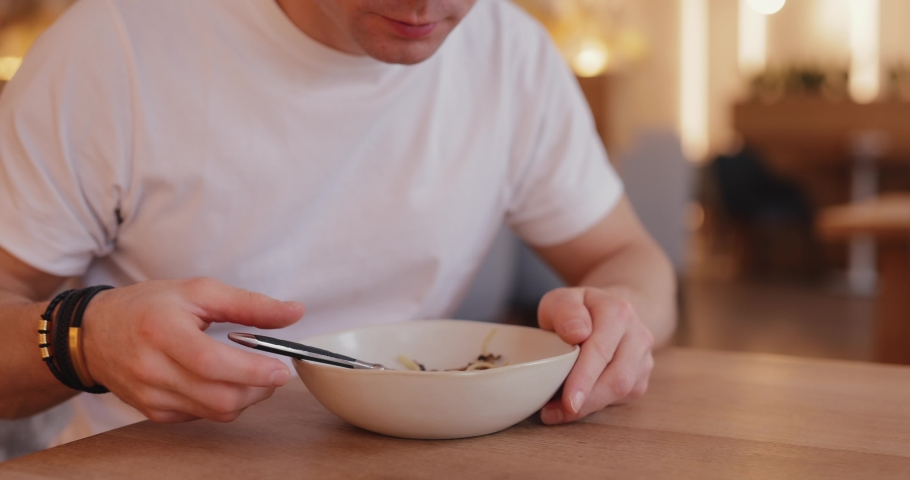 Adult man eating pasta in a cafe close up