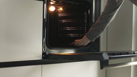 Woman cleaning electric oven after cooking