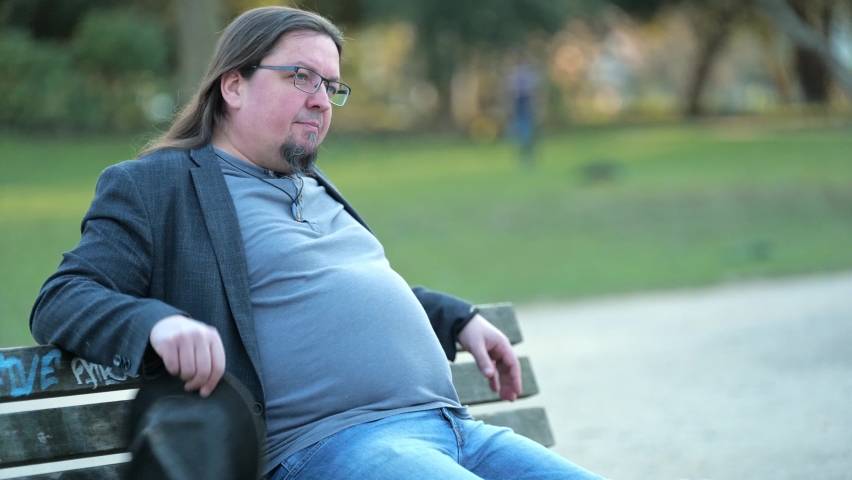 [4k] long haired dude playing with his hat on park bench