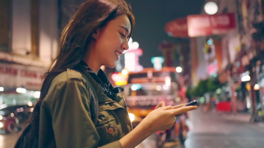 Asian attractive woman backpacker chatting on phone while walk in city. Beautiful woman tourist traveler travel alone on street using smartphone enjoy spend time on holiday vacation trip at night road Royalty-Free Stock Footage #1086567077