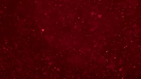 Bokeh of sparkling glittering lights in the shape of hearts flowing and falling across the screen, glowing in red and pink. Magical romantic abstract background. Loop.
