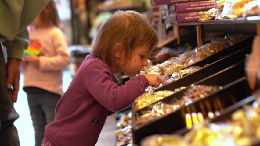 The little toddler girl is choosing sweets with dad while doing shopping in a candy shop Royalty-Free Stock Footage #1086570308