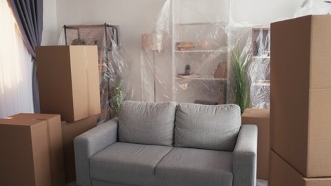 Moving regret. Upset couple. New life. Disappointed middle-aged man and woman covering sofa with plastic film feeling sadness sitting light room interior.