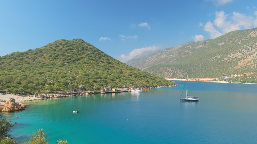 Gorgeous lagoon and small beach with beautiful turquoise water of Mediterranean sea in Kas town, Antalya province, Turkey. Small yacht boat in the Kas bay at a sunny day. Revealing steadicam footage | Shutterstock HD Video #1086574475