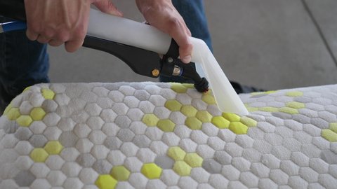 Male Worker Cleaning a mattress With Vacuum Cleaner.Professionally extraction method. Upholstered furniture. Mattress chemical cleaning.