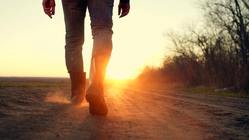 Agriculture. Farmer in rubber boots walk along dirt rural road. Man walk at sunset. Agriculture concept. Farmer inspects plantation. Farm business concept. Dirt rubber boots, in the sun and dust Royalty-Free Stock Footage #1086577631