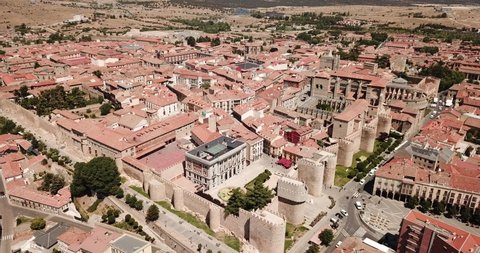 View from drone of reddish roofs of residential buildings and medieval Gothic Cathedral in Spanish fortified city of Avila 