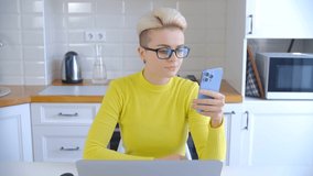 Stylish young woman browsing internet on mobile phone. Tom boy person with short dyed hair using modern smartphone for communication and entertainment. Freelancer female networking online
