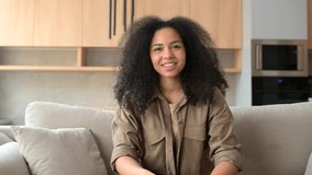 Headshot of biracial young curly woman looking and talking at the camera. Virtual meeting with African-American female colleague or classmate, video call, meeting with tutor or friend on the distance