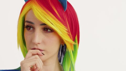 Pretty rainbow-haired caucasian woman playing with her lips and dallying white background close-up shot. High quality 4k footage