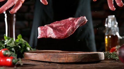 Flying piece of raw beef steak falling on cutting board. Meat preparation in kitchen. Filmed on high speed cinema camera, 1000 fps. Speed ramp effect.
