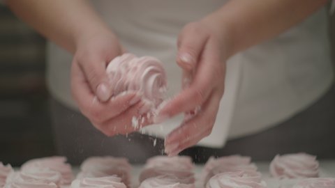 Confectioner's woman hands cooking strawberry marshmallow with sugar powder in slow motion.