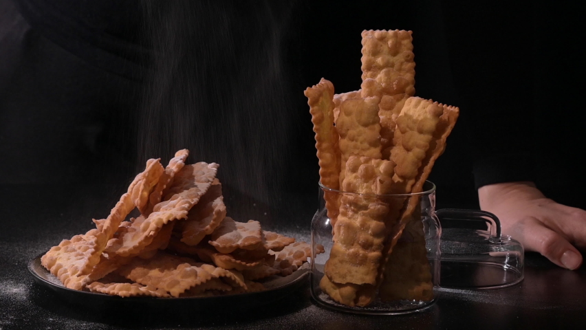 Sfrappole or chiachiere or angel wings. Carnival food TYPICAL. Traditional sweet crisp pastry deep-fried and sprinkled with powdered sugar.crispy dessert festive in female hands. 4k