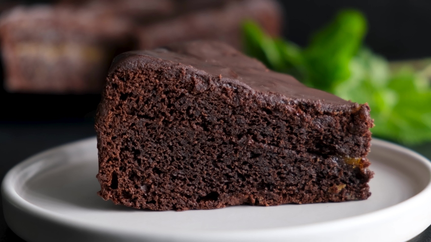 Chocolate icing pouring on slice of dark chocolate fudge cake. Delicious sweet chocolate cake closeup view Royalty-Free Stock Footage #1086590207