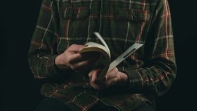 Close up video of man flip through a book over dark background