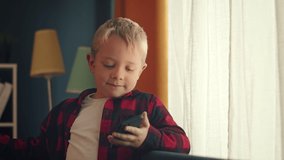 Little boy using smartphone enjoying communication sitting on sofa