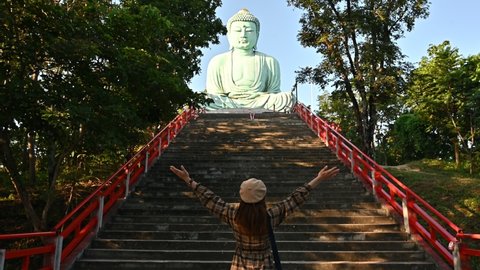 Tourist woman raised her hands while visiting Wat Phra That Doi Phra Chan temple located on the serene top hill in Mae Tha district, Lampang province of Thailand.
