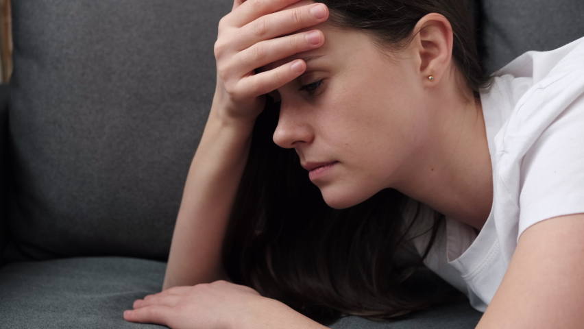 Close up of tired young caucasian woman lying on sofa at home. Portrait exhausted depressed sad female. Chronic fatigue, lack of energy, breakdown, frustrated by personal problems troubles concept | Shutterstock HD Video #1086601571