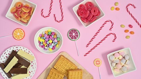 6k Colorful candies, sweets, lollypops, chocolates appear on pastel pink theme. Stop motion flat lay