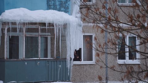 Nizhny Novgorod, January 27, 2022.  An elderly woman knocks icicles out of the window of her apartment
